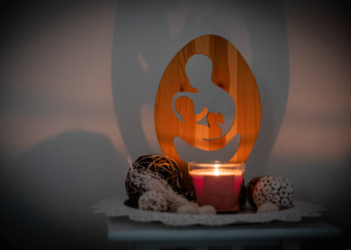 Holzdekoration zeigt Mutter mit ihrem Kind und einer Kerze daneben